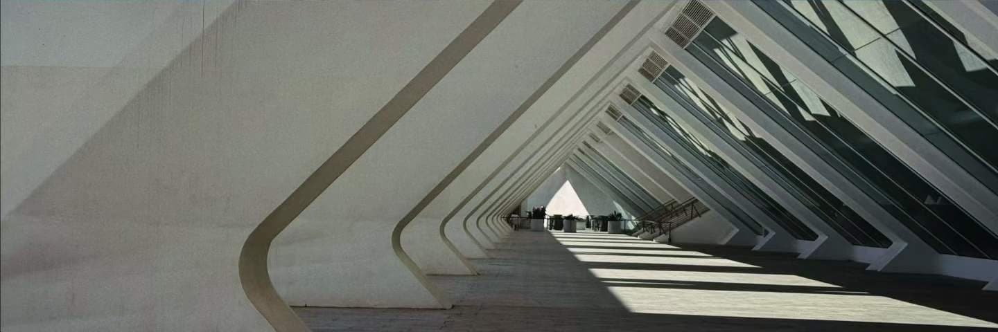 Repeating white concrete ribs of a modern building, curving away in perspective.