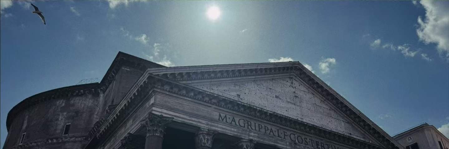The columned portico of a classical temple with the sun burning directly over its pediment.